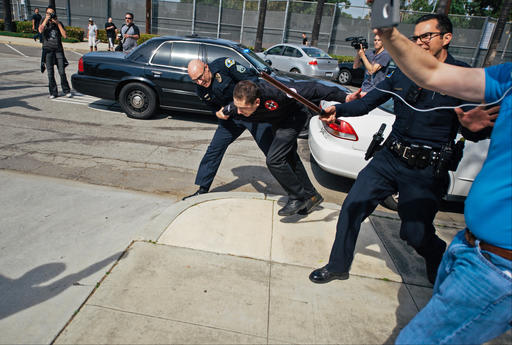 Hood  OC Weekly shows. a Ku Klux Klansman member is apprehended by Anaheim Police Department officers after members of the KKK tried to start an anti-immigration rally at Pearson Park in Anaheim