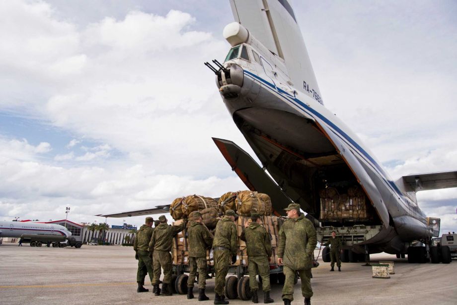 Russian air force personnel prepare to load humanitarian cargo on board a Syrian Il-76 plane at Hemeimeem air base in Syria. Russia’s defense ministry said Tuesday