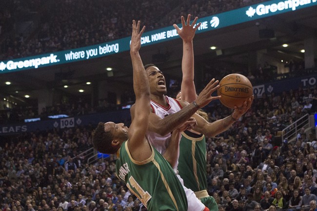 Toronto Raptors De Mar DeRozan centre shoots on Boston Celtics Evan Turner left and Kelly Olynyk during second half NBA basketball action in Toronto on Friday