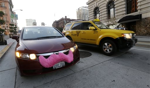 Lyft driver Nancy Tcheou waits in her car after dropping off a passenger as a taxi cab passes her in San Francisco. The final destination is a mystery but General Motors is taking another step on its fast-moving journey into