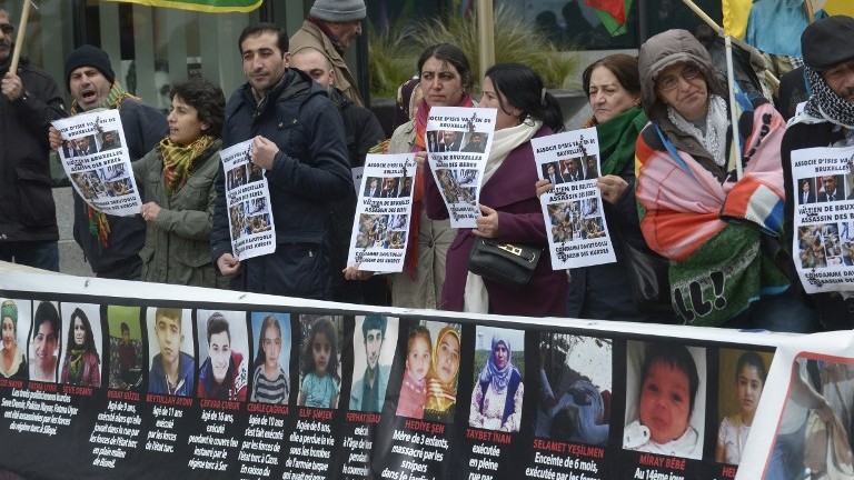 Kurdish people hold placards depicting Turkish leaders and reading'partner of the Islamic State group' as they take part in a protest to call for an end of the Turkish State terror in Kurdistan during the European Union summit in Brussels on March