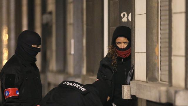 Masked Belgian police secure the entrance to a building in Schaerbeek during police operations following