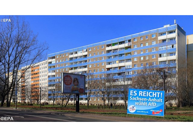 A campaign poster of the Alternative for Germany party reading 'Es reicht! Sachsen Anhalt wählt AfD&#39  standing in front of a building complex.- EPA