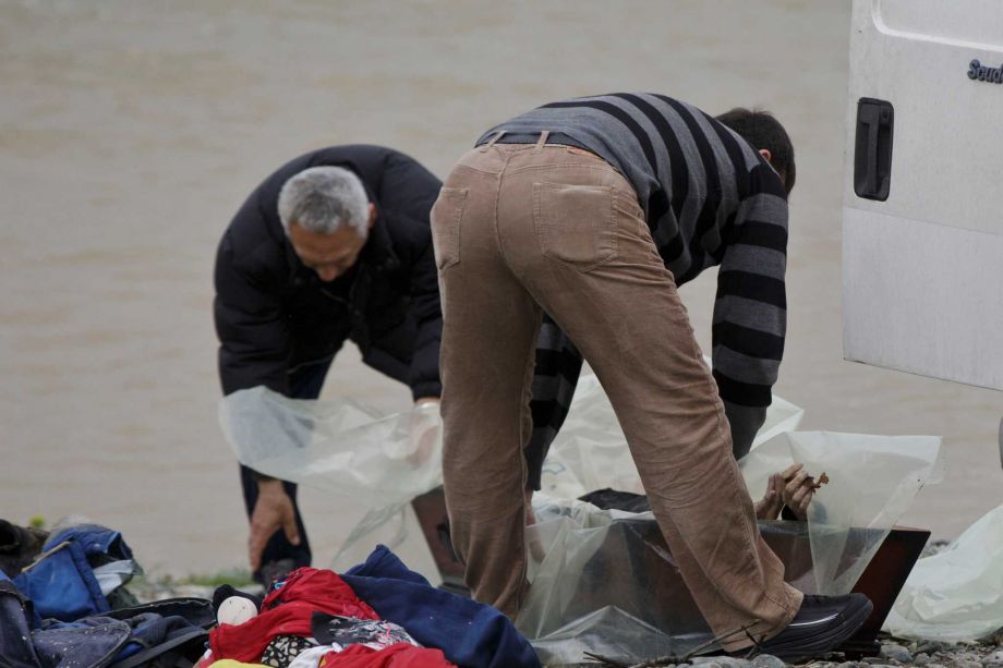 Macedonian coroners place the body of a drowned migrant in a coffin on the river bank of Suva Reka river near the southern Macedonian town of Gevgelija Monday