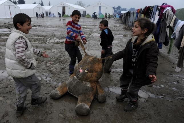 Refugee children play with a stuffed toy at a muddy makeshift camp at the Greek Macedonian border near the village of Idomeni Greece