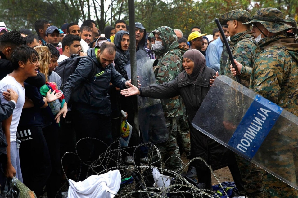 A Syrian woman begs a Macedonian soldier to allow members of her family to cross