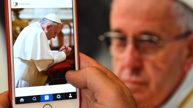 A man looks at the Instagram account of Pope Francis in Rome. The pontiff joined the