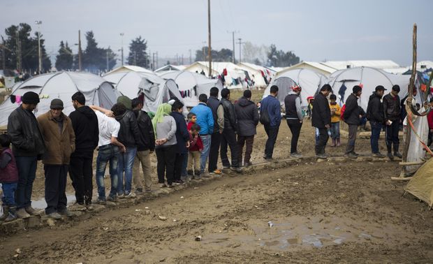 Refugees wait in queues to get food at the Idomeni refugee camp in Greece