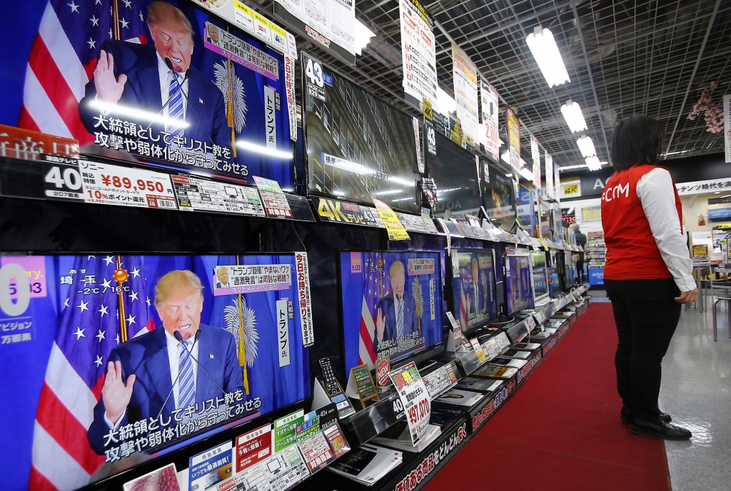 A salesclerk stands in front of flat-panel TVs showing Republican