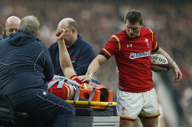 Wales’ captain Sam Warburton gives a thumbs up and a pat of support from Dan Biggar as he is driven off on a stretcher with an injury during the Six Nations international rugby match between England and Wales at Twickenham stadium in London Saturday M