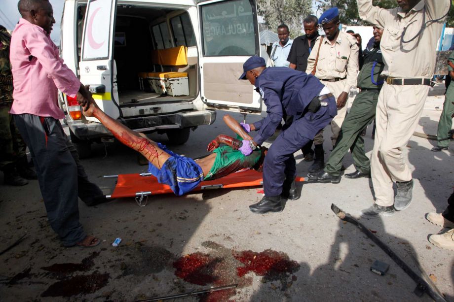 Somali police officers carry a suspected suicide car bomber wounded in a bombing outside a police academy in Mogadishu Somalia Wednesday