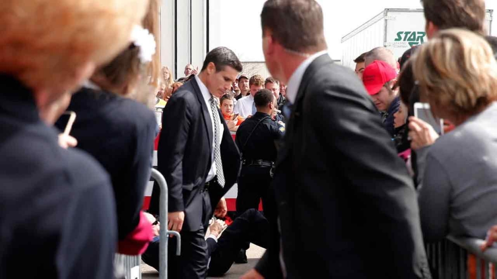 People are seen on the ground after a man tried to breach the security buffer during a campaign rally with Trump on Saturday