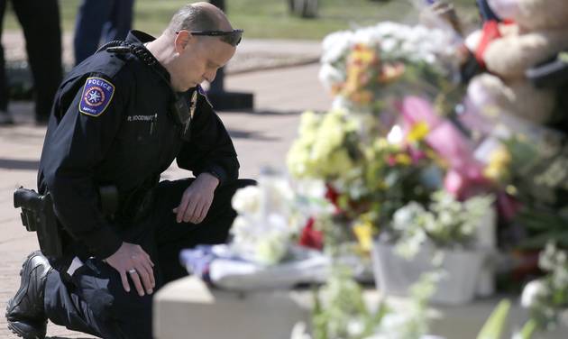 DFW Airport Police officer Robert Woodward kneels in front of a makeshift memorial for a slain officer at the Euless Police Department Wednesday