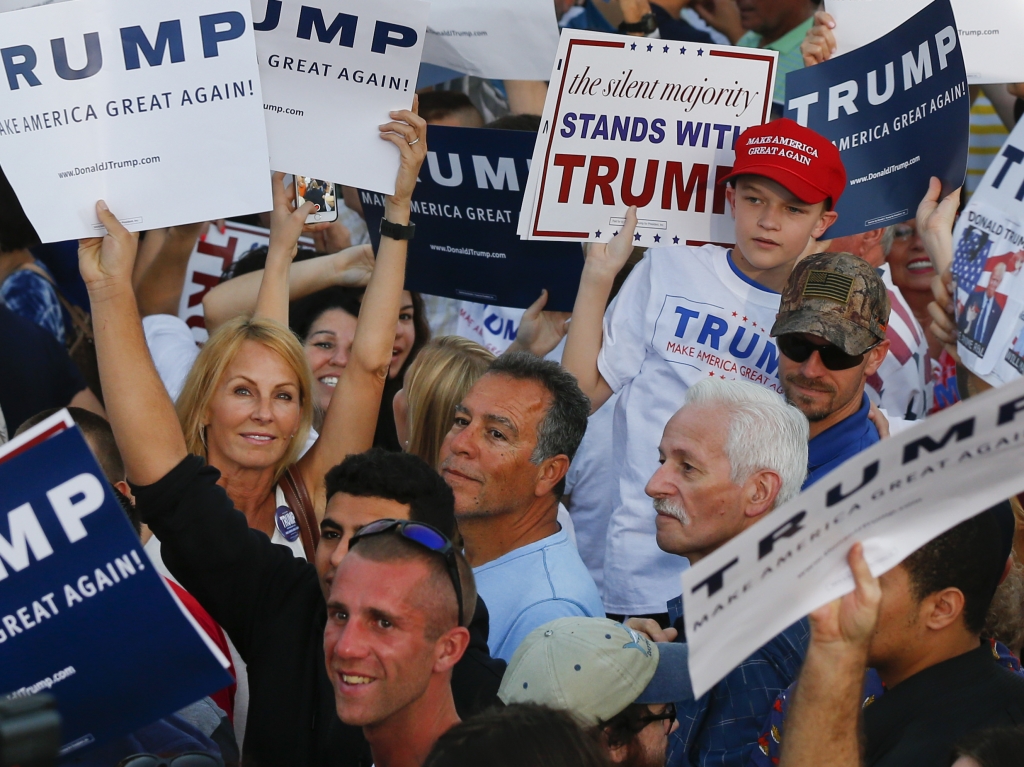 Audience members hold up signs supporting Republican presidential candidate Donald Trump during a campaign rally in Boca Raton Fla. on Sunday