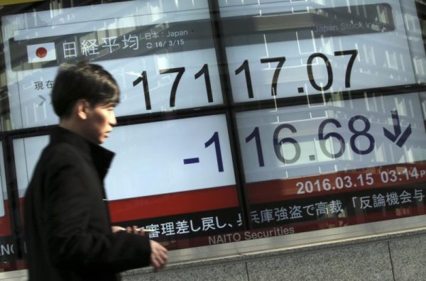 A man walks past an electronic stock price