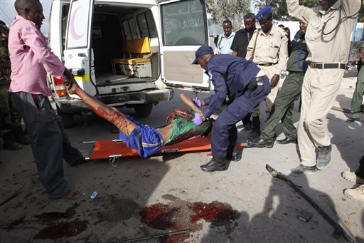 Somali police officers carry a suspected suicide car bomber wounded in a bombing outside a police academy in Mogadishu Somalia Wednesday