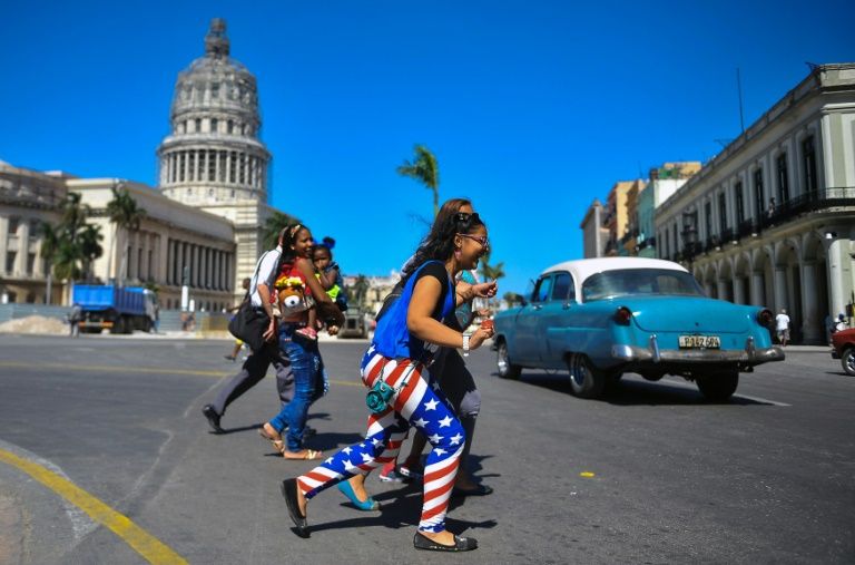 A woman wearing leggings with the colours of the US flag walks along a street of Havana