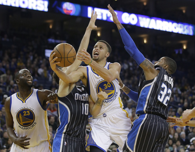 Golden State Warriors Stephen Curry shoots between Orlando Magic's Evan Fournier and C.J. Watson during the second half of an NBA basketball