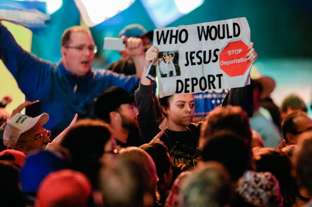 A demonstrator waves a sign during an election rally of Republican presidential candidate Donald Trump in Kansas City Mo. Saturday