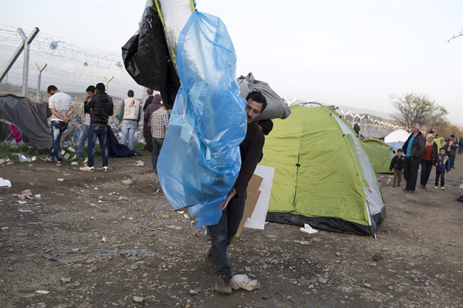 A man carries his tent in front of the wire fence that separates the Greek side from the Macedonian one at the northern Greek border station of Idomeni Tuesday March 1 2016. Some 7,000 migrants including many from Syria and Iraq are crammed into a