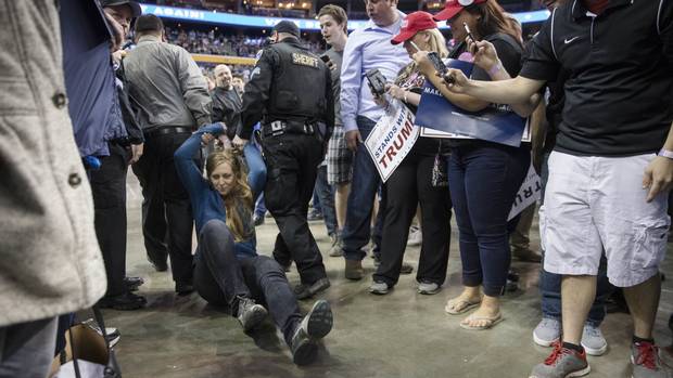 A protester is dragged away by authorities as Republican presidential candidate Donald Trump speaks during a campaign stop in Buffalo New York