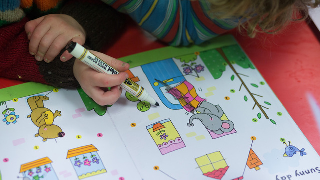 A young girl draws at a playgroup for pre-school aged children