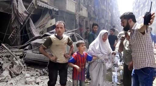 In this image made from video and posted online from Validated UGC a man leads a woman in tears and child out of the scene after airstrikes hit Aleppo Syria Thursday