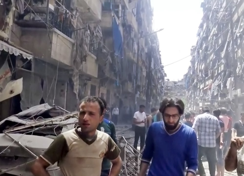 Men look at damaged buildings after airstrikes hit the rebel-held part of the contested city of Aleppo Syria on Thursday killing more than a dozen people