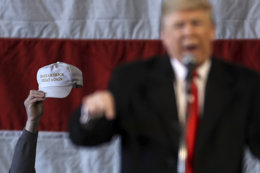 A man holds a'Make America Great Again hat as U.S. Republican presidential candidate Donald Trump as he speaks during a campaign event at an airplane hanger in Rochester New York