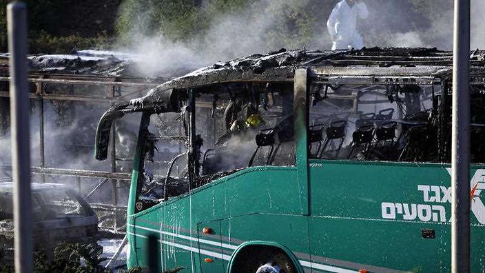 An Israeli firefighter is seen inside a burnt bus in Jerusalem Monday