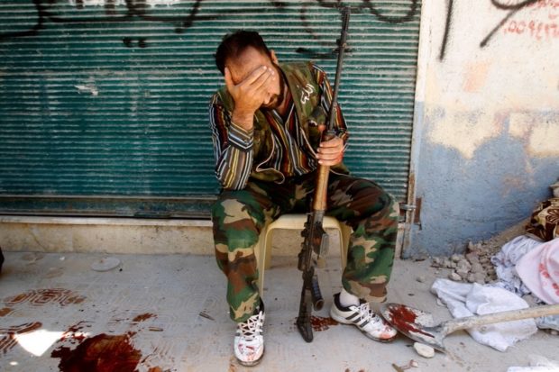 Anti-government fighter hides his face after his friend was shot by a Syrian army sniper. /Reuters