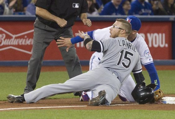 Brett Lawrie dives back to third base after over running the bag as Toronto Blue Jays Troy Tulowitzki applies the tag during the fifth inning of a baseball game Tuesday