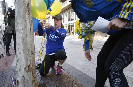 Brooke Kelly center and Willette Keegan right set up a makeshift memorial at the site of the first detonation on the third anniversary of the Boston Marathon bombings Friday