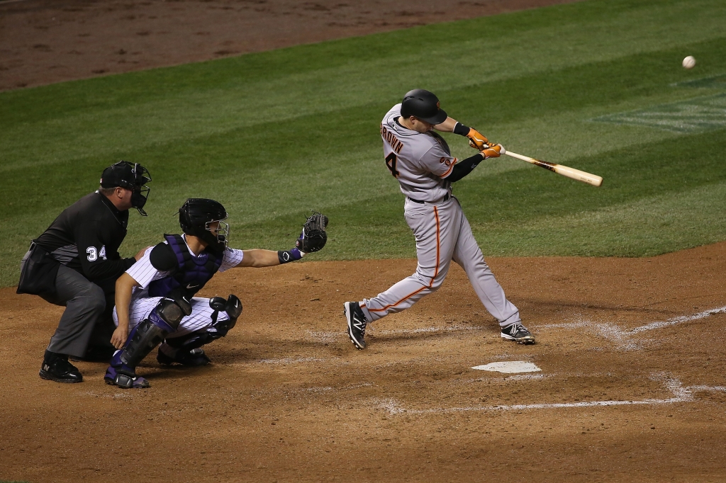 Trevor Brown #14 of the San Francisco Giants hits a two run home run off of Tyler Chatwood #32 of the Colorado Rockies as catcher Nick Hundley #4 of the Colorado Rockies backs up the plate and umpire Sam Holbrook oversees the action as the Gaints take a 5