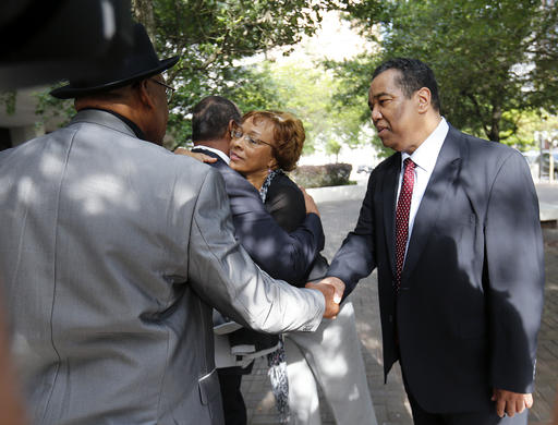 Dr. Romell Madison right brother of Ronald Madison who was gunned down by New Orleans police on the Danziger Bridge in the days following Hurricane Katrina shakes hands with family friend Malik Rahim as Romell's wife hugs Madison's brother Lance out