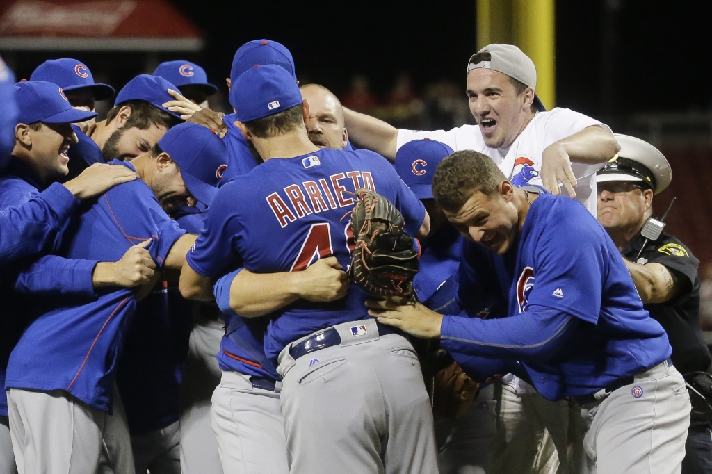 A fan top right who ran onto the field celebrates with Chicago Cubs starting pitcher Jake Arrieta and his teammates after Arrieta throw a no-hitter against the Cincinnati Reds in a baseball game Thursday