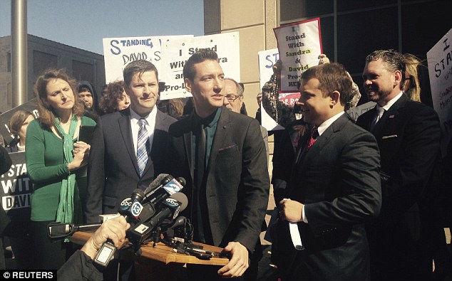 Daleiden speaks at a news conference outside a court in Houston with a group of supporters behind him