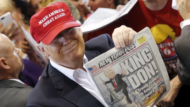 Donald Trump holds up the front page of the New York Post as he signs autographs at a rally with supporters in Harrington Del. on Friday. The Republican presidential front-runner has vowed not to tamp down his boisterous personality as he edges closer