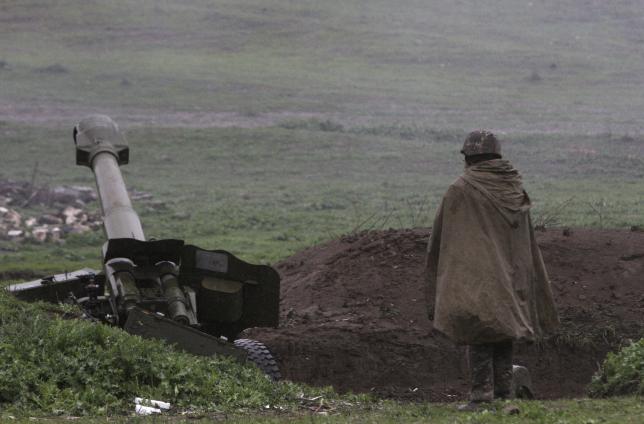 An Armenian soldier of the self-defense army of Nagorno Karabakh stands near an artillery unit in the town of Martakert where clashes with Azeri forces are taking place in Nagorno Karabakh region which is controlled by separatist Armenians. REUTERS  Va