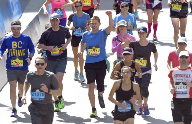 Patrick Downes raises his arm as he approaches the finish line during the 120th running of the Boston Marathon