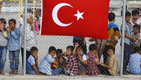 A refugee man stands with children as they wait for the arrival of German Chancellor Angela Merkel and EU President Donald Tusk at a refugee camp near Gaziantep Turkey