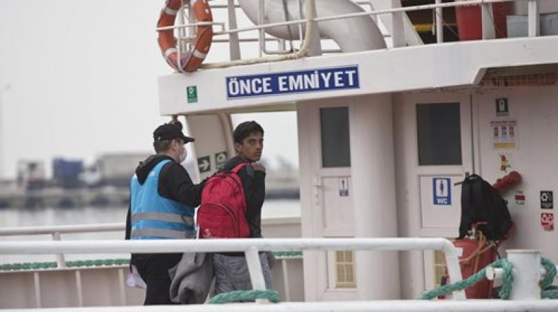 Pakistani migrant looks back as he gets on a ferry for Turkey in the port of Mytilini of the Greek island of Lesbos