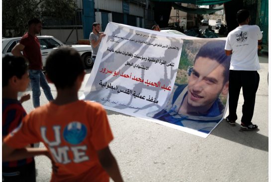 Young Palestinians carry a poster bearing the image of Abdel Hamid Abu Sorur who has been hailed a martyr for his attack on a bus in Jerusalem