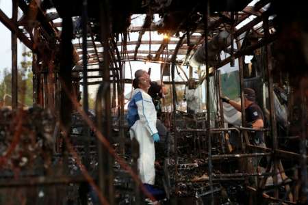 Israeli forensics experts search in the remains of a burnt-out a bus after a bomb blast ripped through the vehicle in Jerusalem