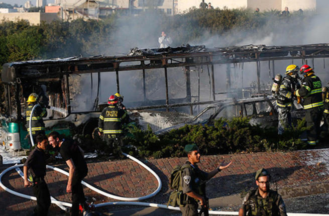 Israeli security forces stand guard as firemen extinguish a burning bus following an attack in Jerusalem