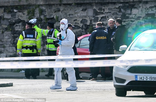 Murder Garda officers and detectives one in a forensics suit gather evidence at the scene of the shooting