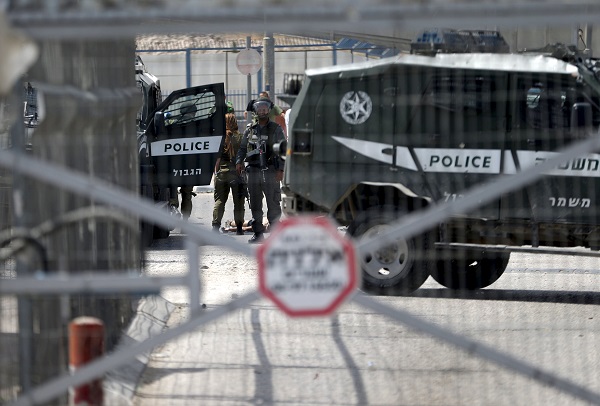 Israeli security forces gather around the body of a Palestinian after he was shot dead by Israeli troops at Qalandia checkpoint near the West Bank city of Ramallah