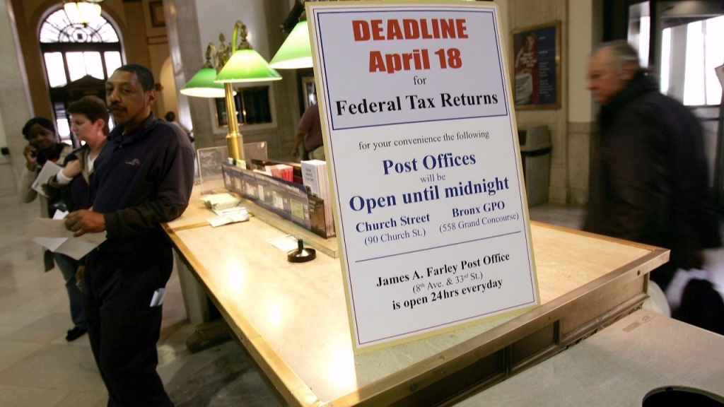 People walk past a sign declaring tax deadline day