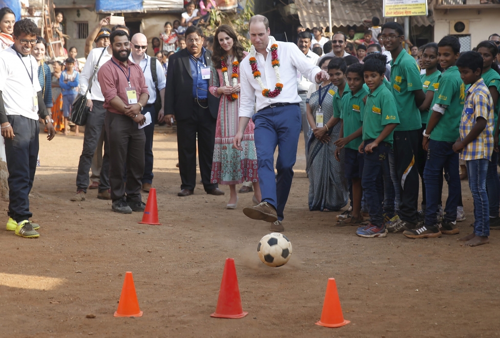 Prince William plays with a football as Kate watches during their visit to a slum in Mumbai on Apr. 10 2016