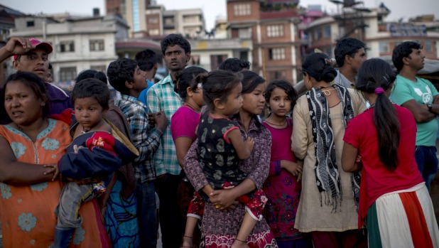 Residents of Kathmandu who moved out in the open and set up temporary tents stand in line to get emergency help